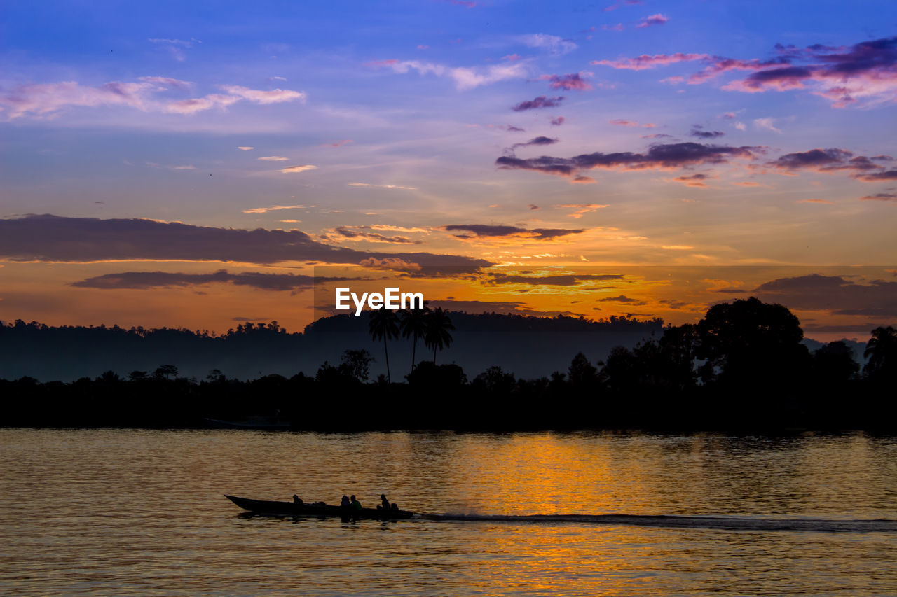 Silhouette people on boat against sky during sunset