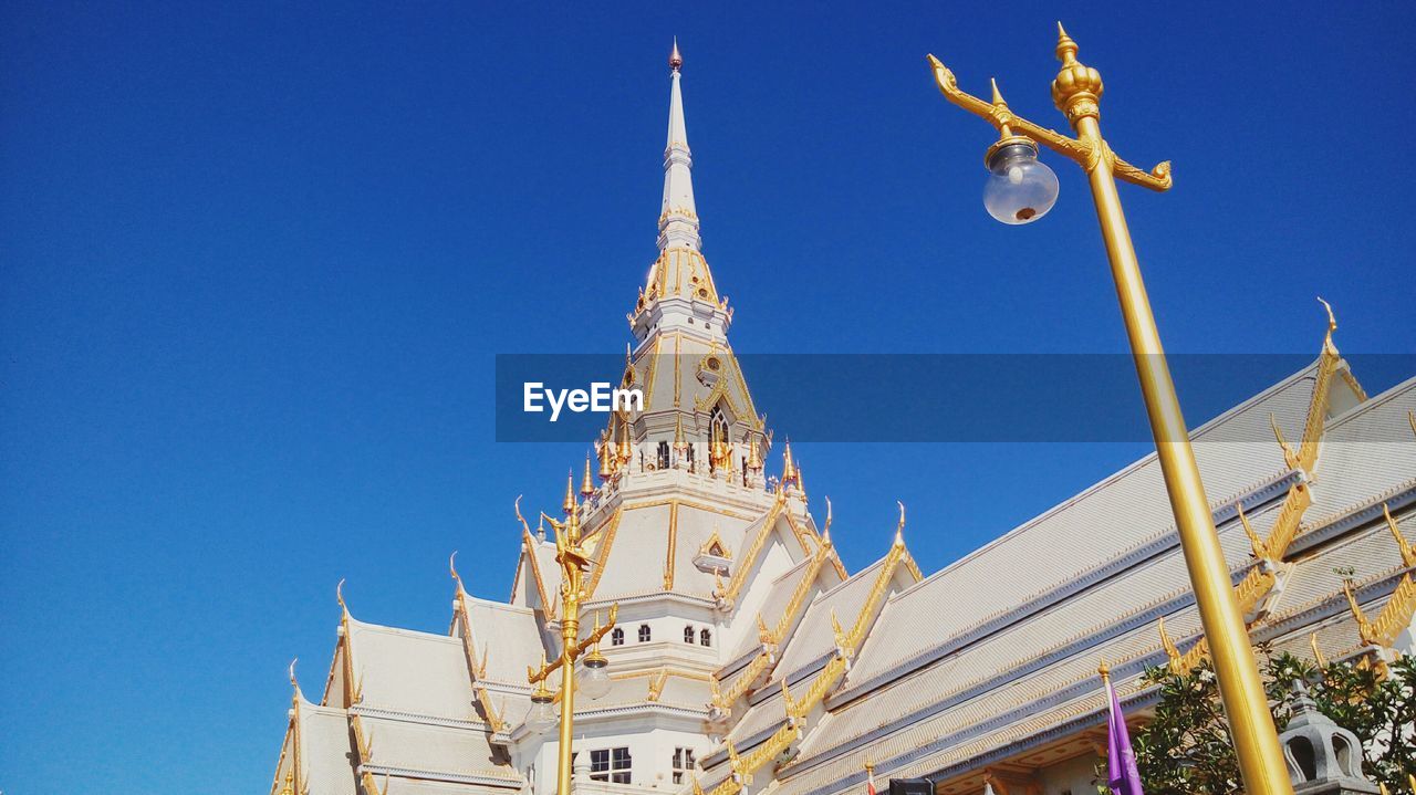 Low angle view of thai temple against clear blue sky