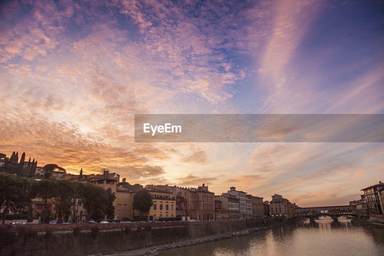 River by city against sky during sunset