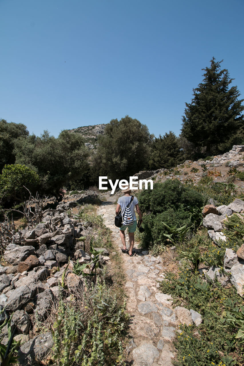 Rear view of woman walking on footpath by ruined buildings