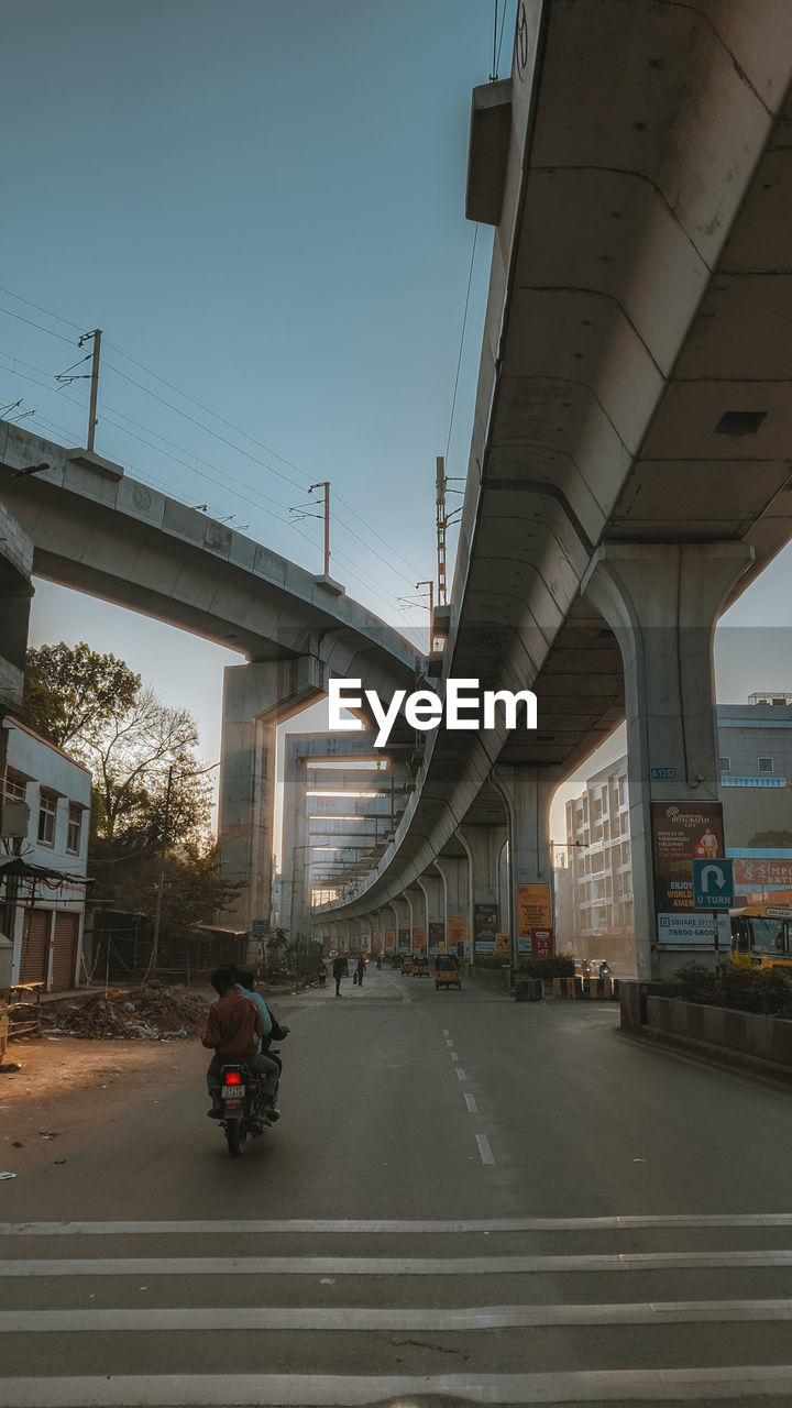 architecture, transportation, built structure, bridge, overpass, road, city, street, transport, mode of transportation, urban area, sky, building exterior, lane, highway, nature, travel, travel destinations, day, land vehicle, city life, motor vehicle, public transport, outdoors, infrastructure, car, sign, clear sky, city street, motion, no people