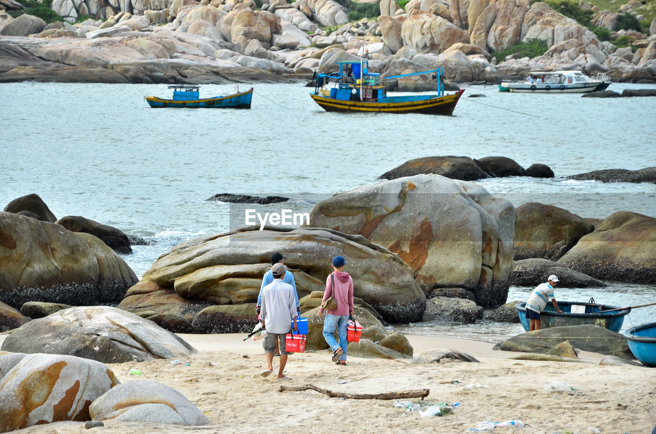 People walking on rock by sea