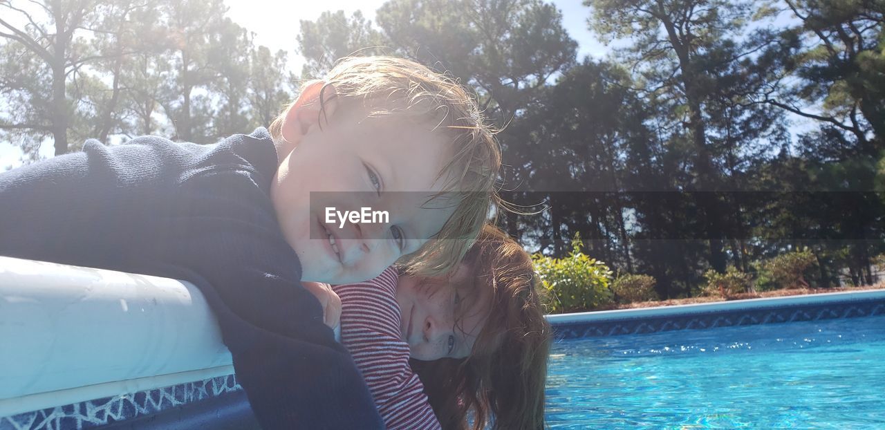 Portrait of boy and girl relaxing by swimming pool