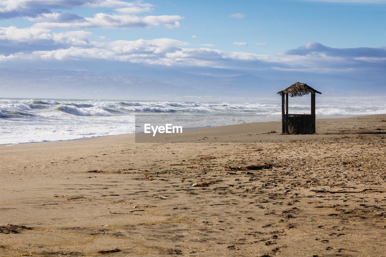 Scenic view of beach against cloudy sky