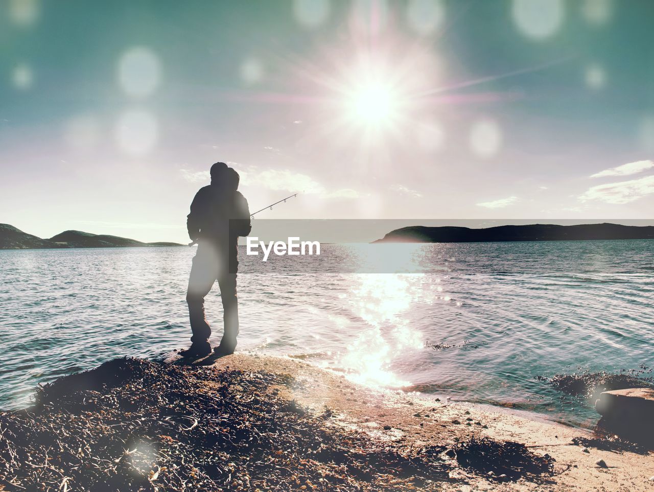 water, one person, sky, sea, nature, ocean, standing, land, adult, beach, beauty in nature, sunlight, horizon, full length, wave, scenics - nature, men, leisure activity, vacation, holiday, trip, rear view, tranquility, sun, back lit, solitude, lens flare, coast, shore, silhouette, cloud, outdoors, lifestyles, person, travel, tranquil scene, day, travel destinations, sunbeam, motion, reflection, idyllic, mountain, relaxation, activity, summer