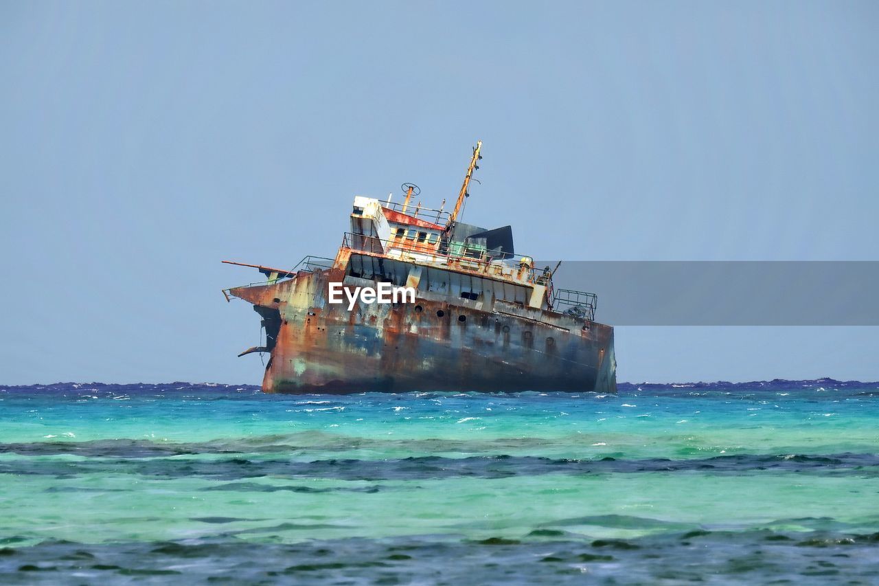 Abandoned ship in sea against clear sky