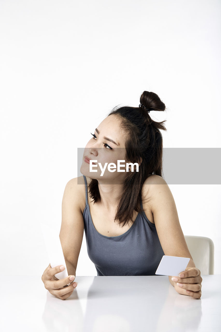 YOUNG WOMAN SITTING ON TABLE WITH WHITE BACKGROUND