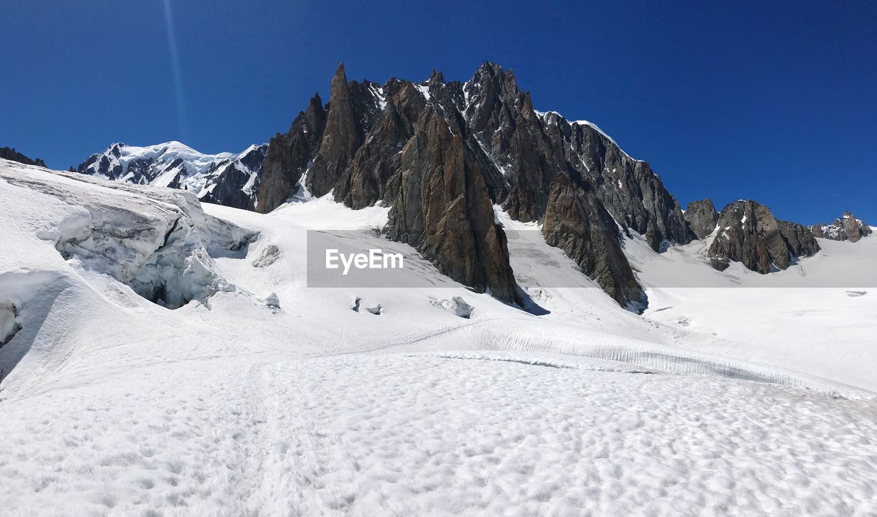 Scenic view of snow mountains against clear blue sky