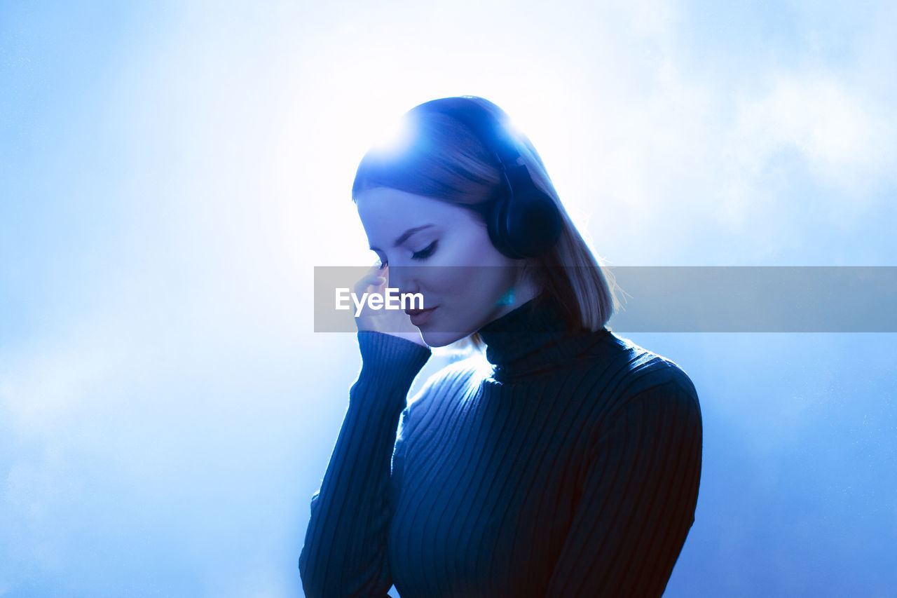 Girl with headphones listening to music with light behind