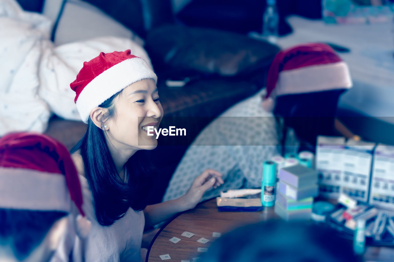 Portrait of happy smiling woman in santa hat playing game with friends at christmas holiday time