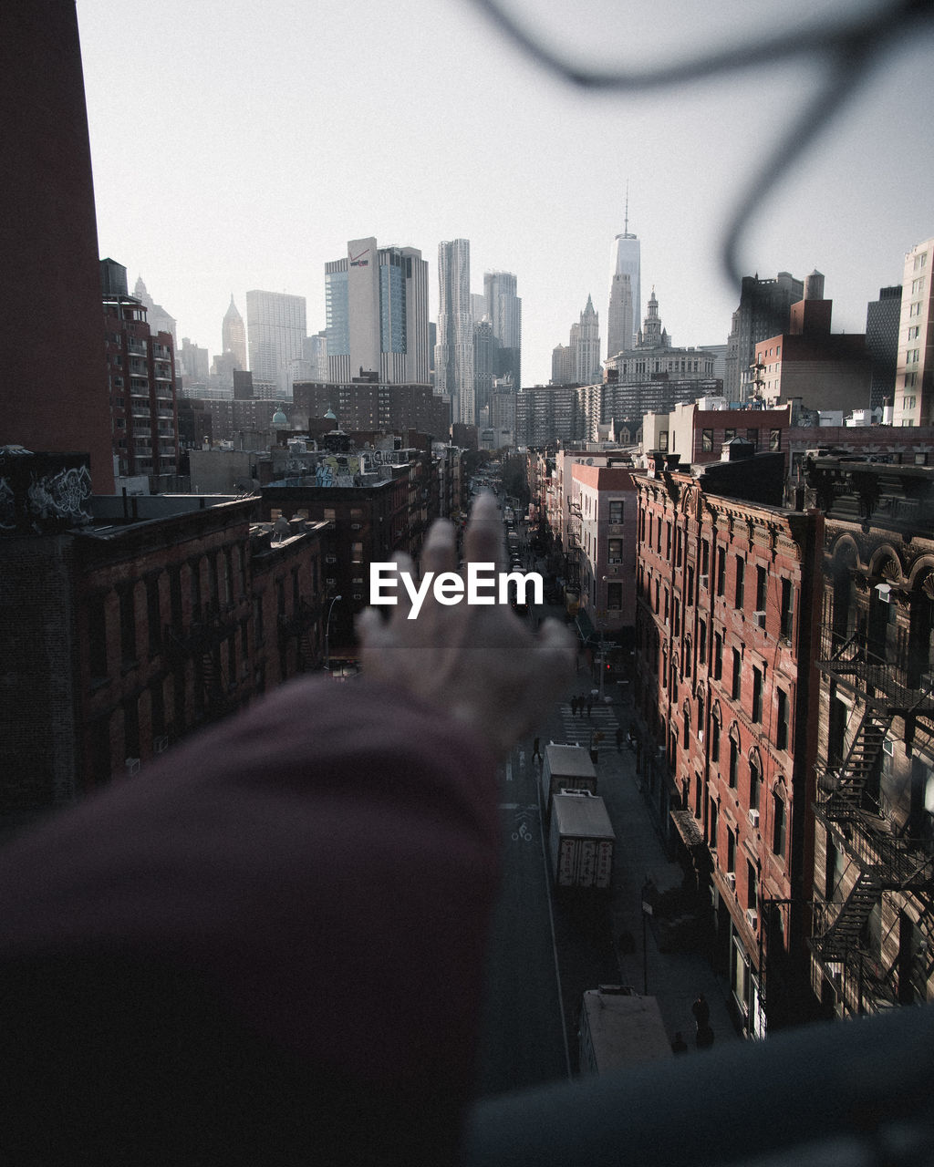 Cropped hand of person against buildings in city