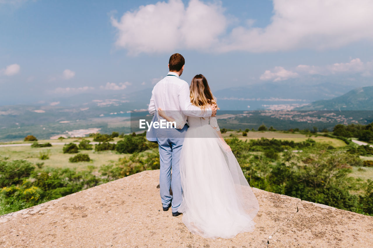 Rear view of married couple standing at observation point against sky