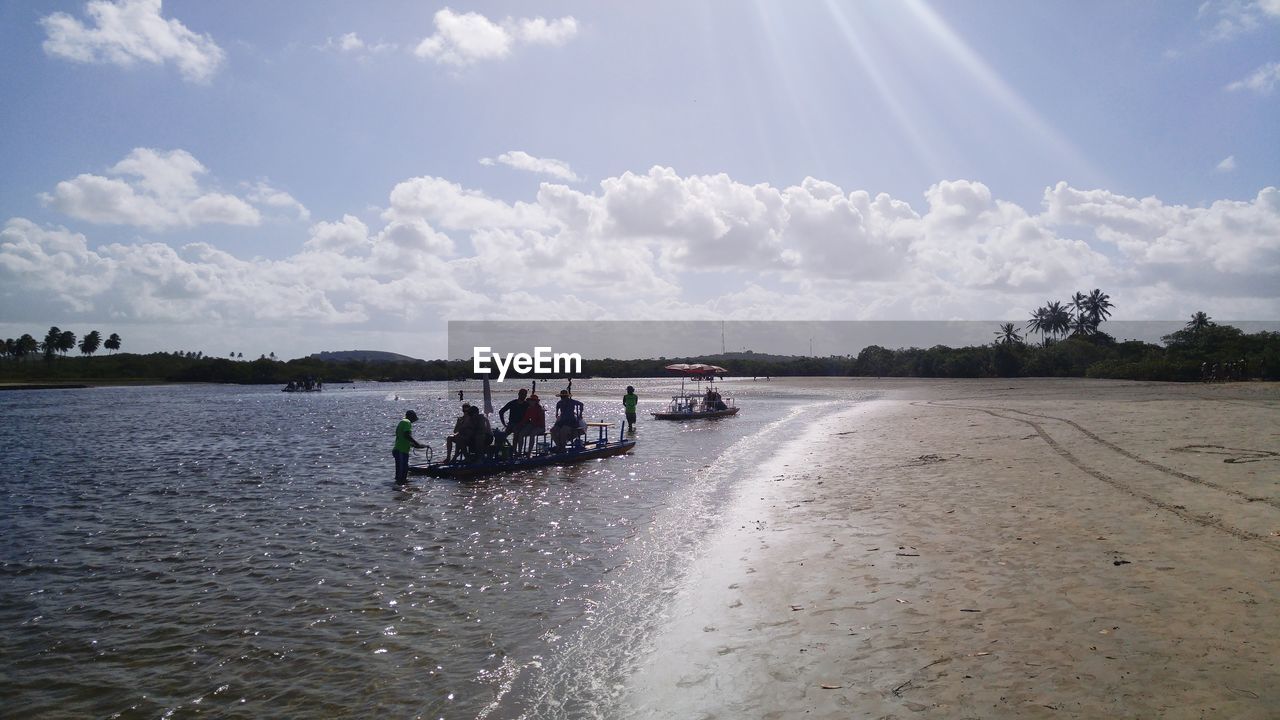 People in boat on shore at beach against sky