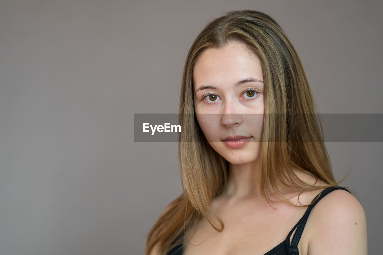 Portrait of a beautiful young woman over grey background