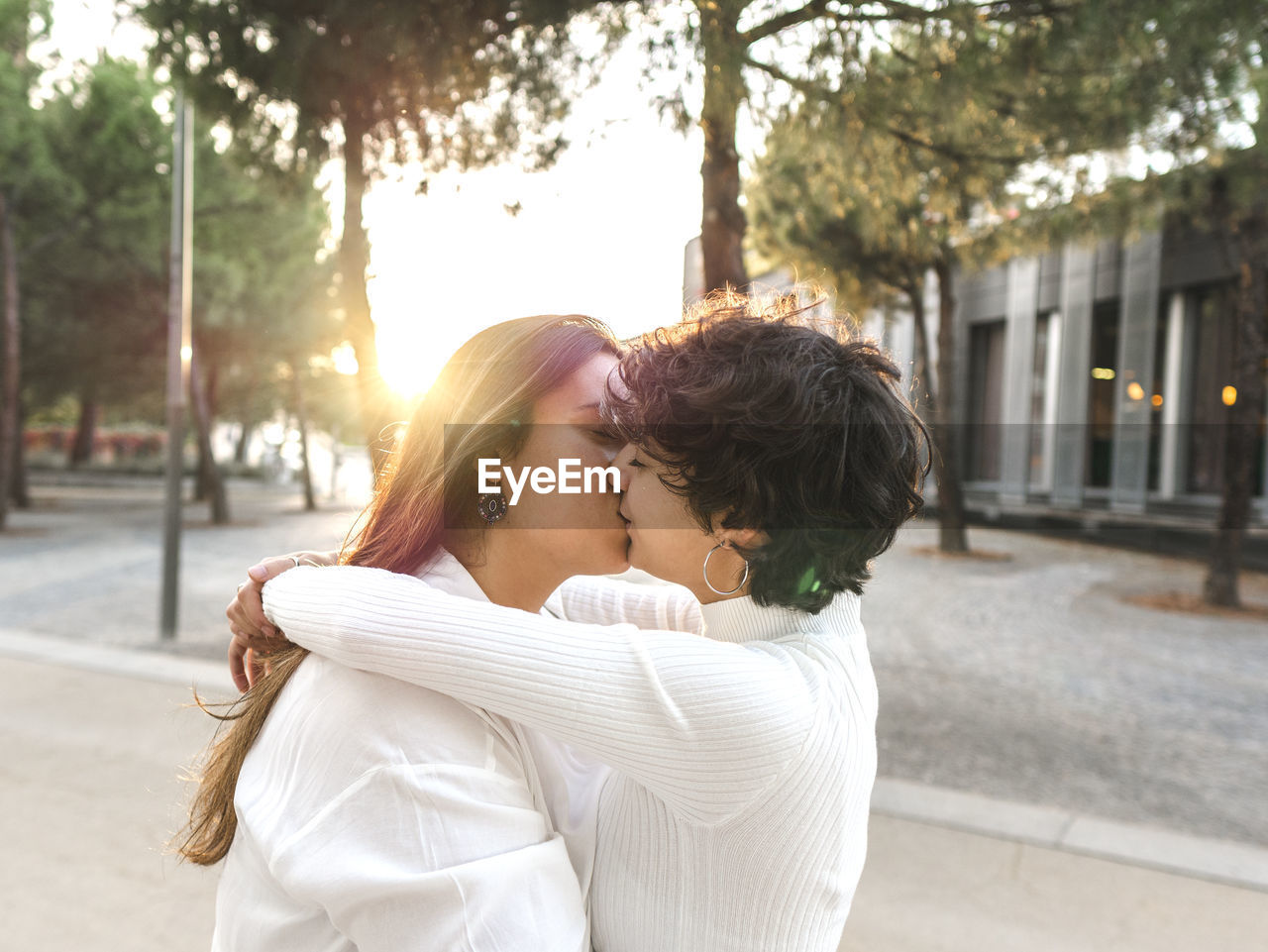 Affectionate lesbian couple embracing and kissing each other at street