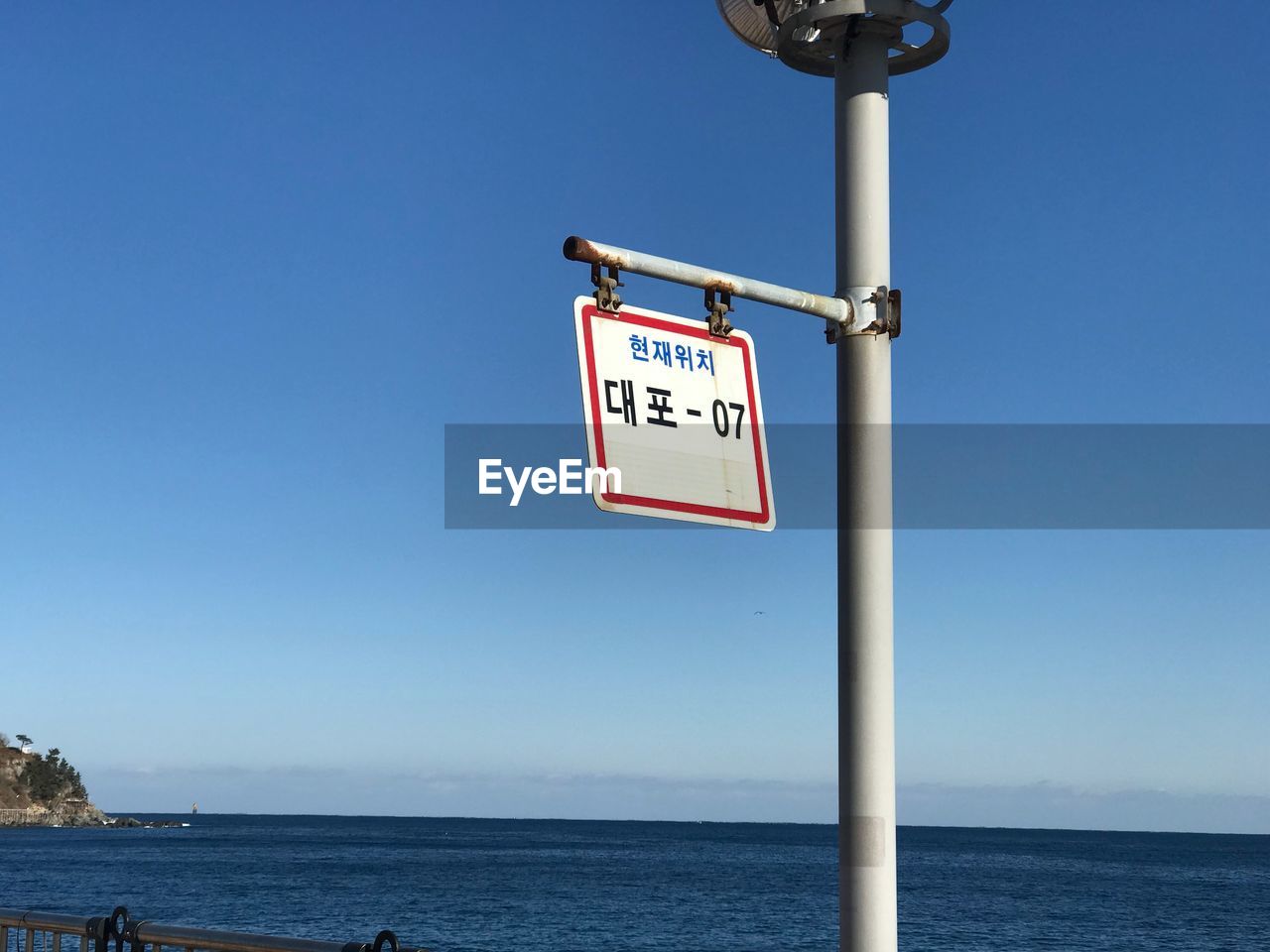 CLOSE-UP OF SIGN BY SEA AGAINST CLEAR SKY