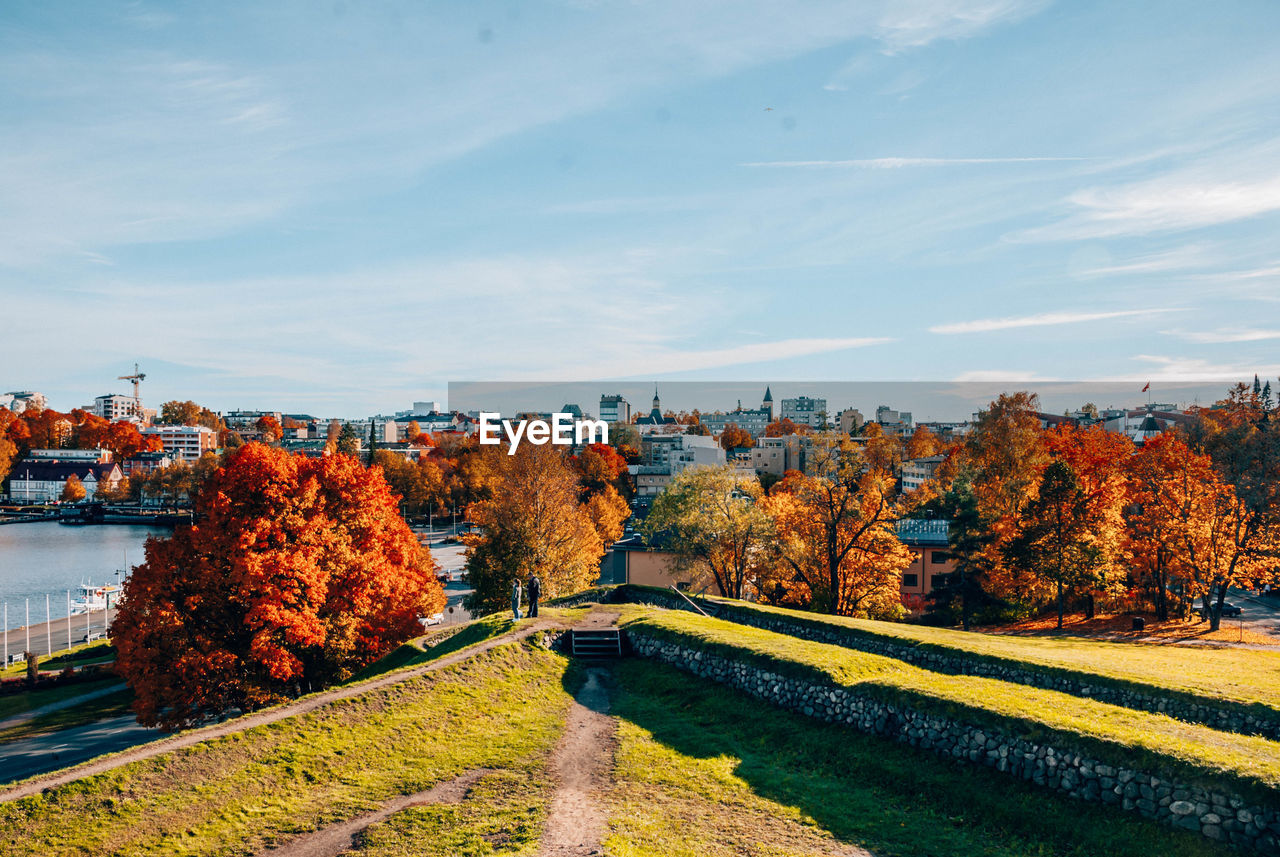 AUTUMN TREES BY CANAL AGAINST SKY