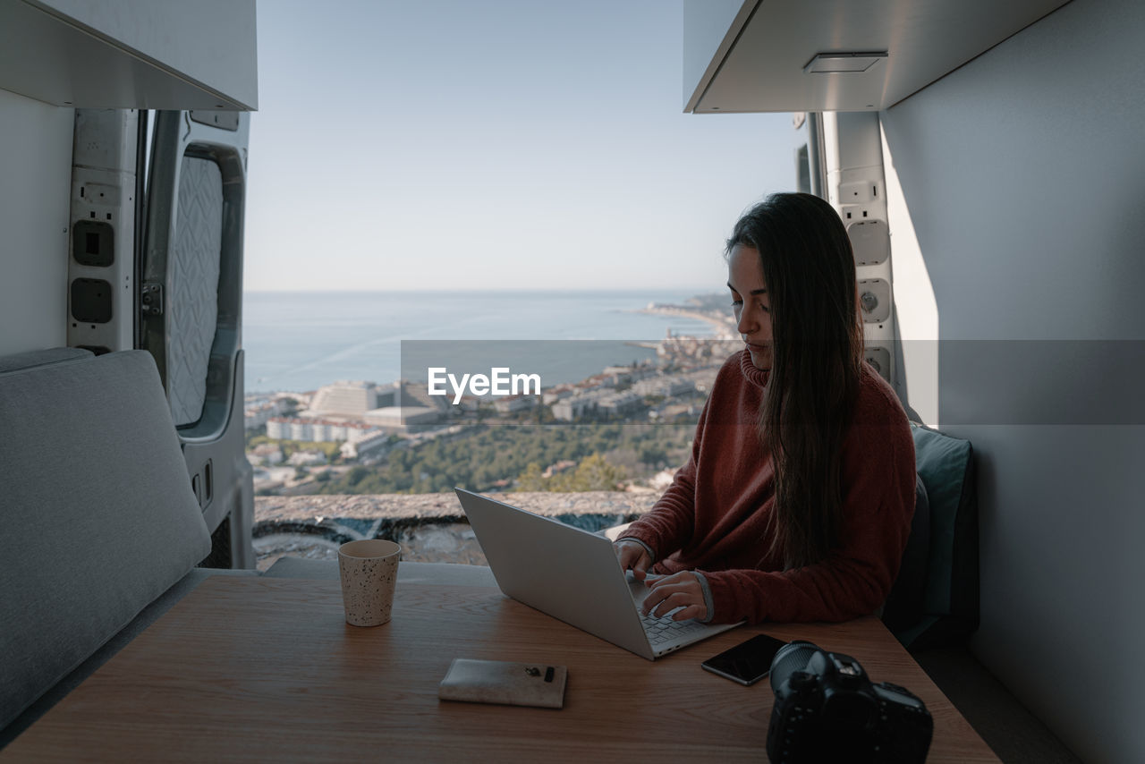 Woman sitting at table working with laptop in vehicle