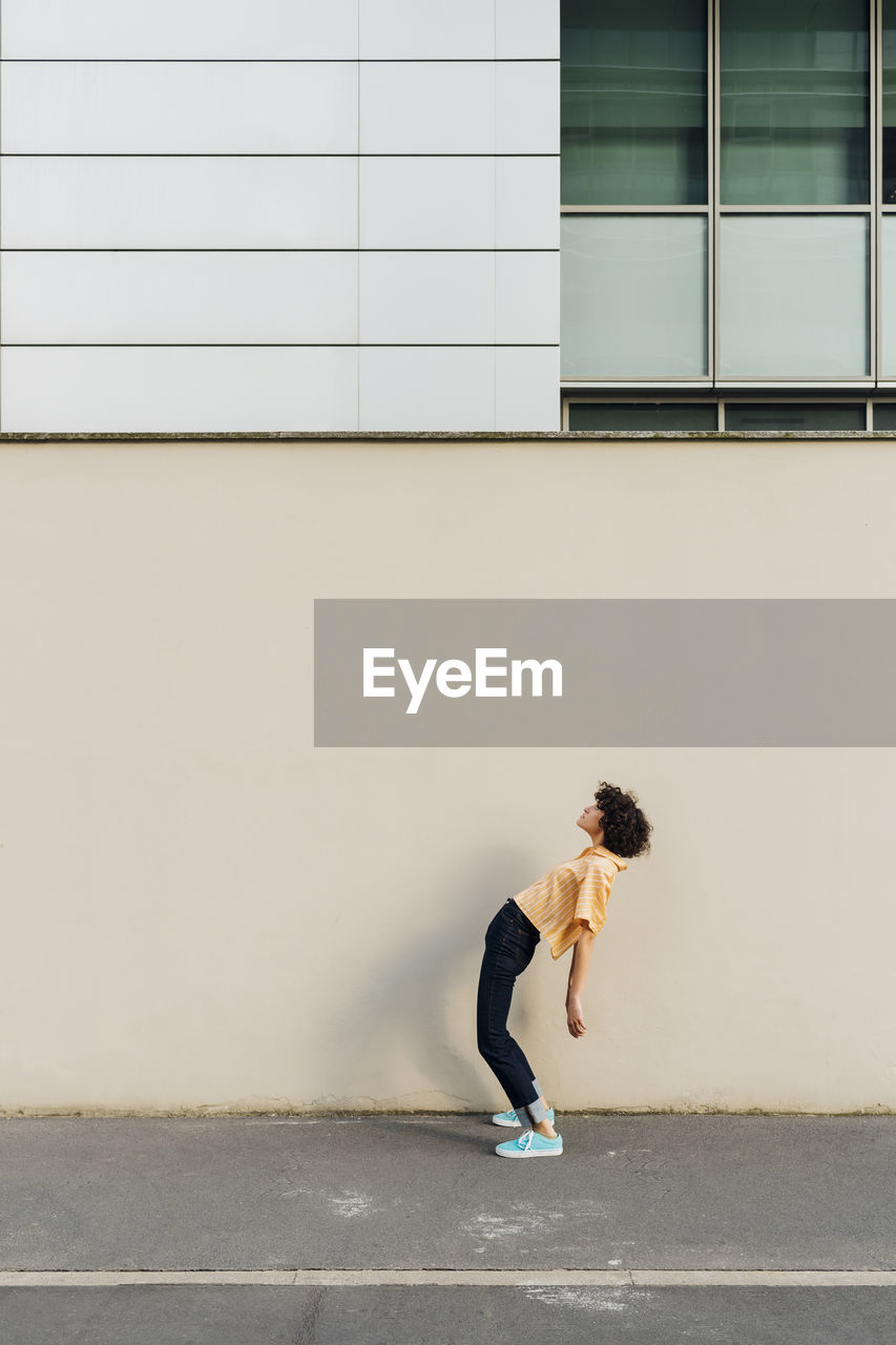 Woman bending backwards in front of wall