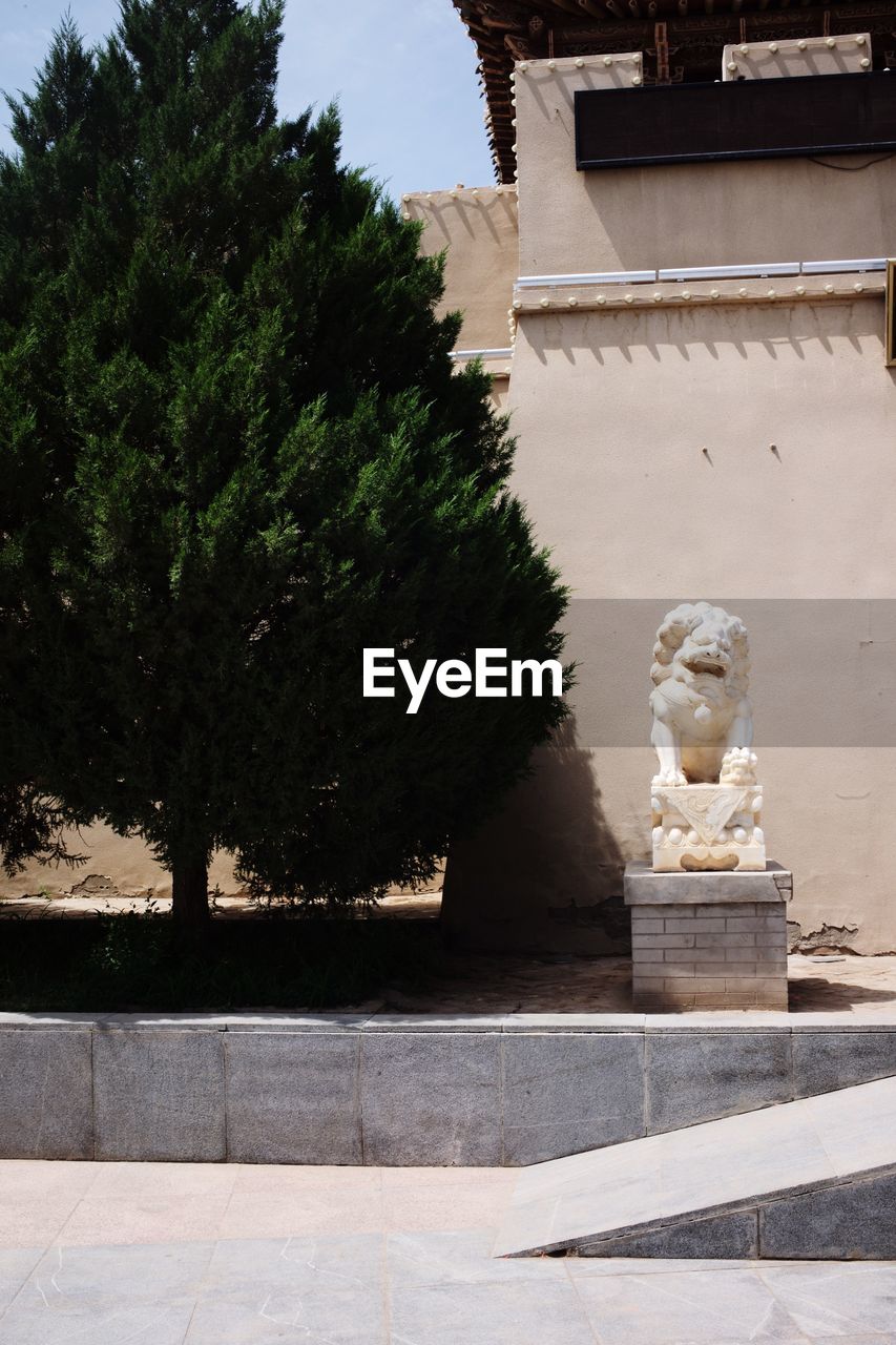 STATUE AGAINST TREES AND BUILDING