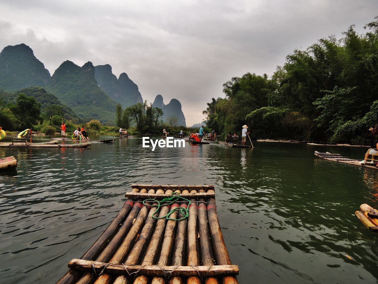 Wooden rafts in river against cloudy sky