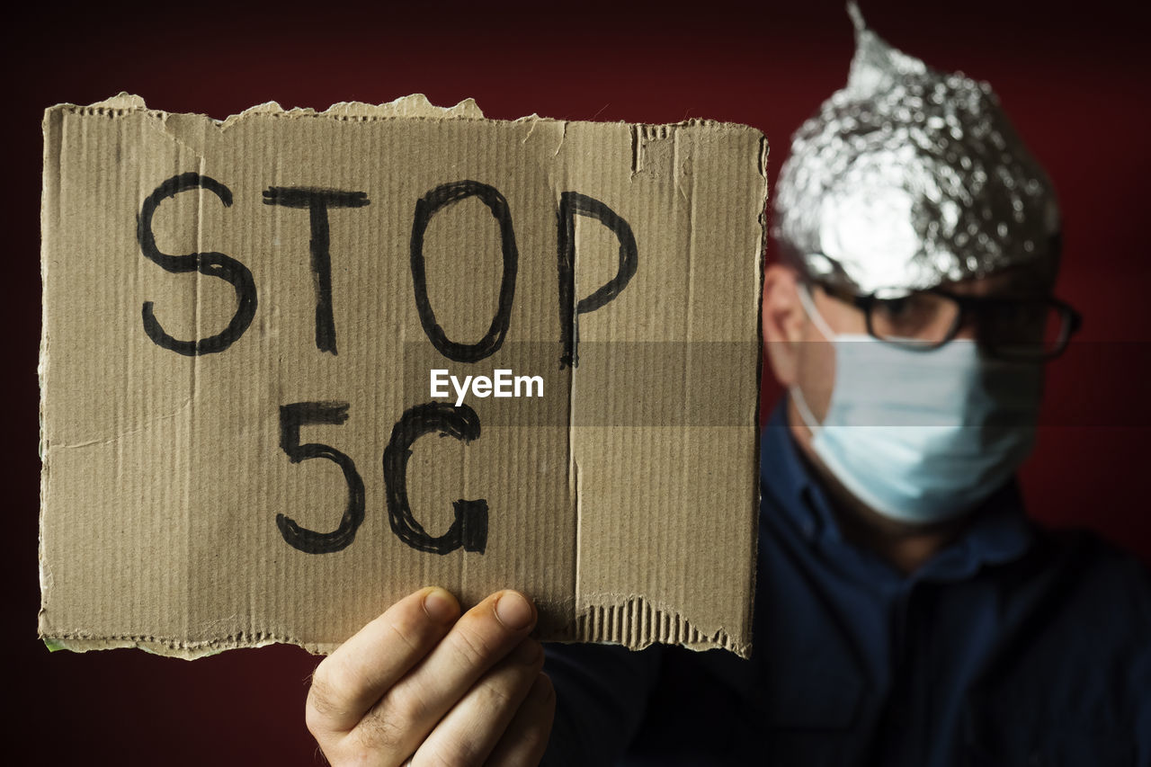 A man in a protective cap made of aluminum foil with a 5g stop banner. coronavirus fake news concept