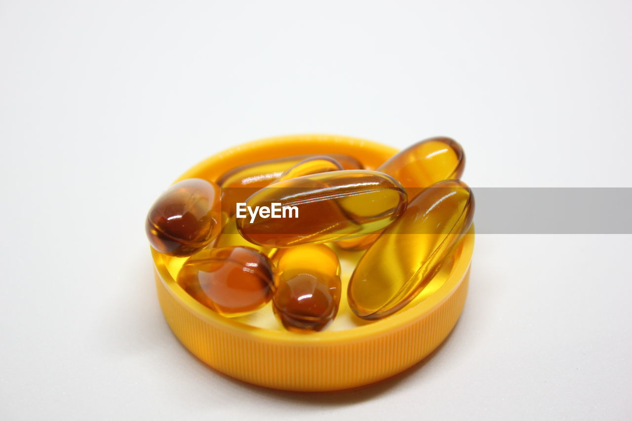 High angle view of capsules on container over white background