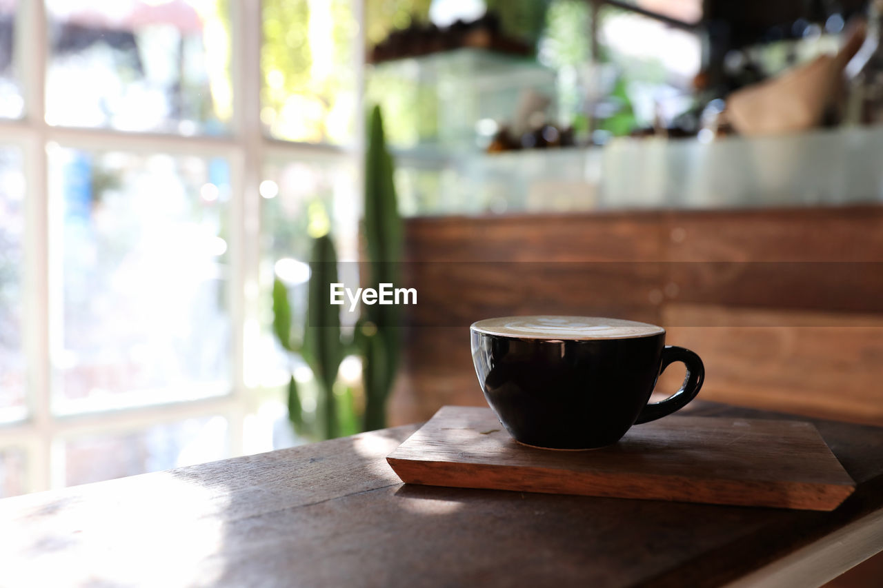 COFFEE CUP ON TABLE AGAINST WALL