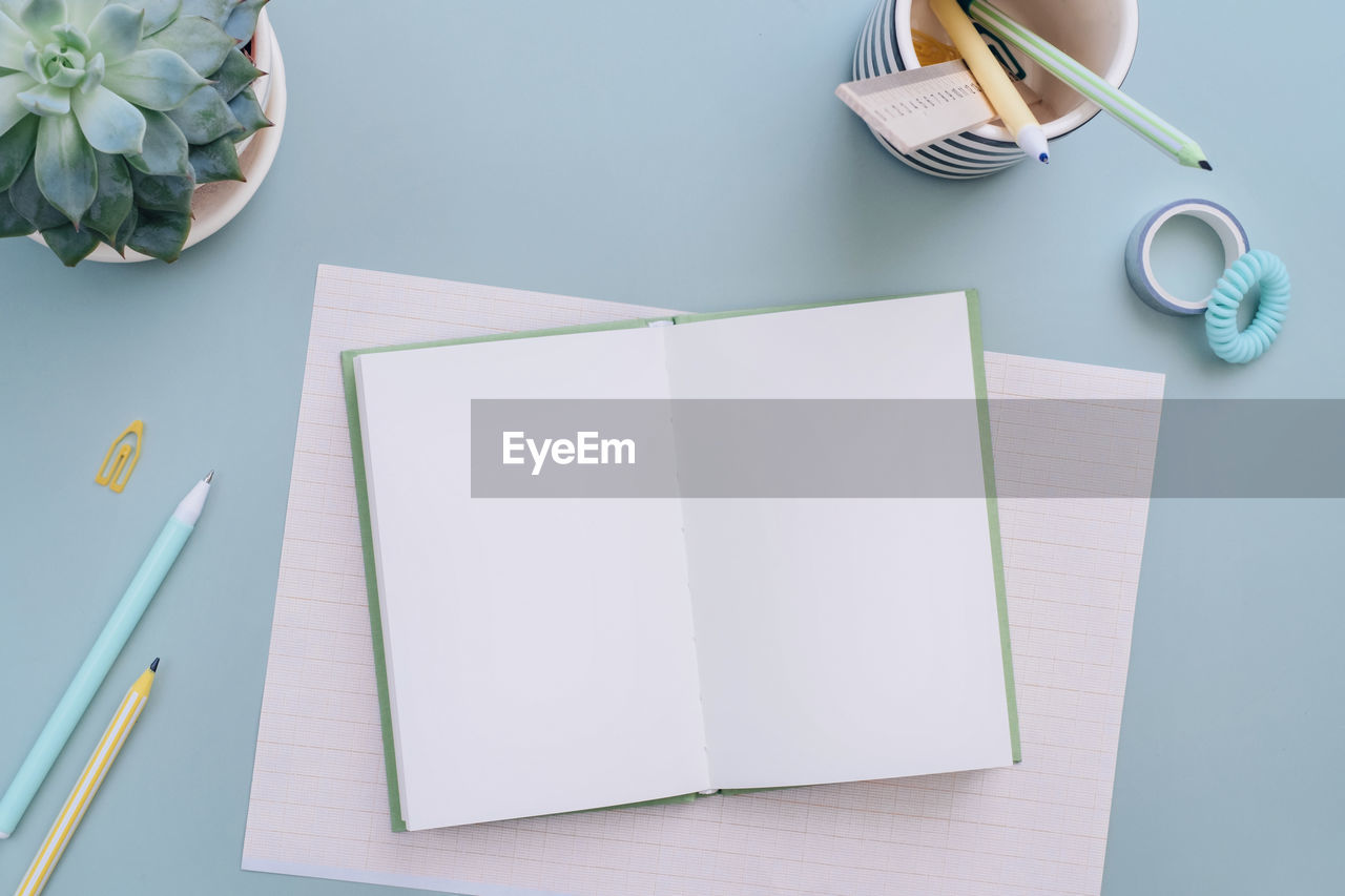 directly above shot of book and pen and note pad with diary with eyeglasses and objects on table