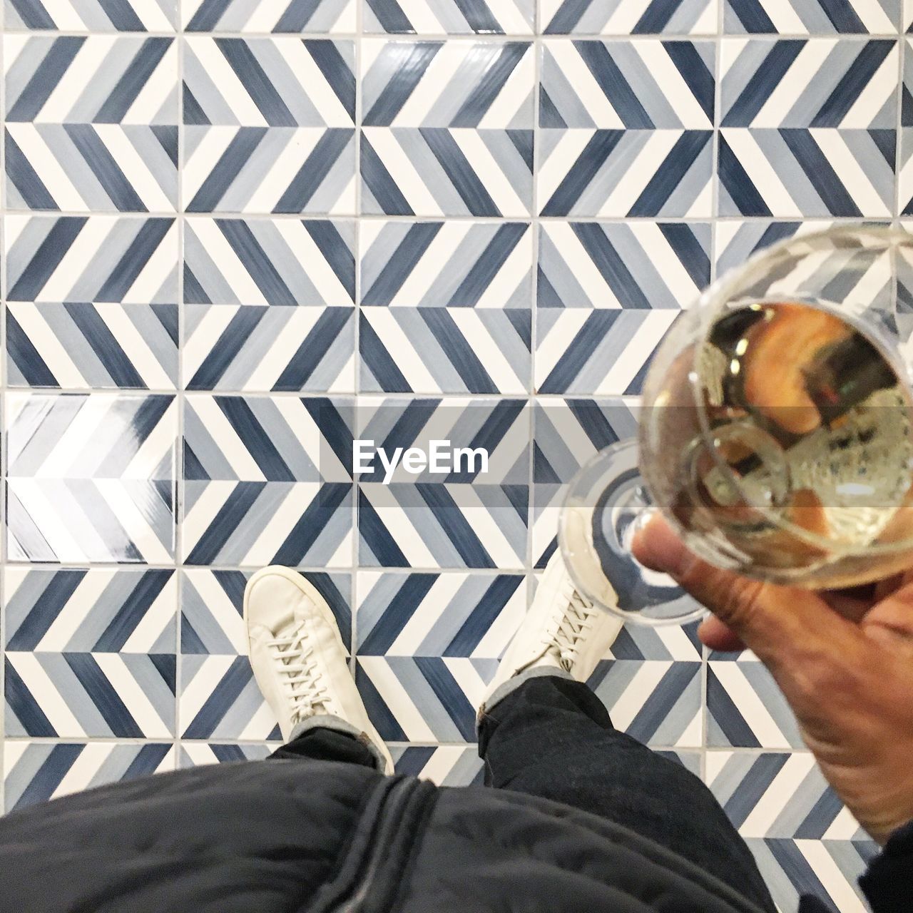 Low section of man holding champagne over patterned floor