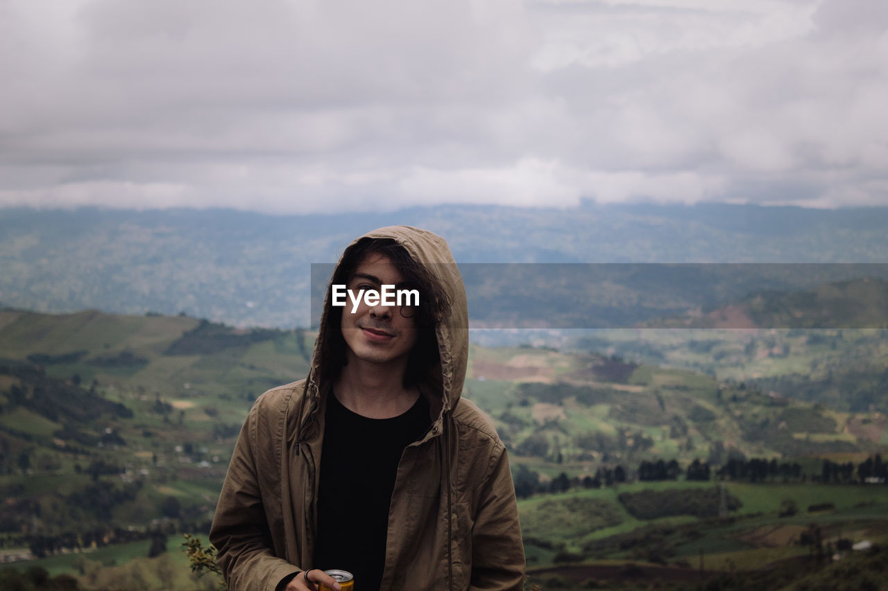 Portrait of young man standing against mountains