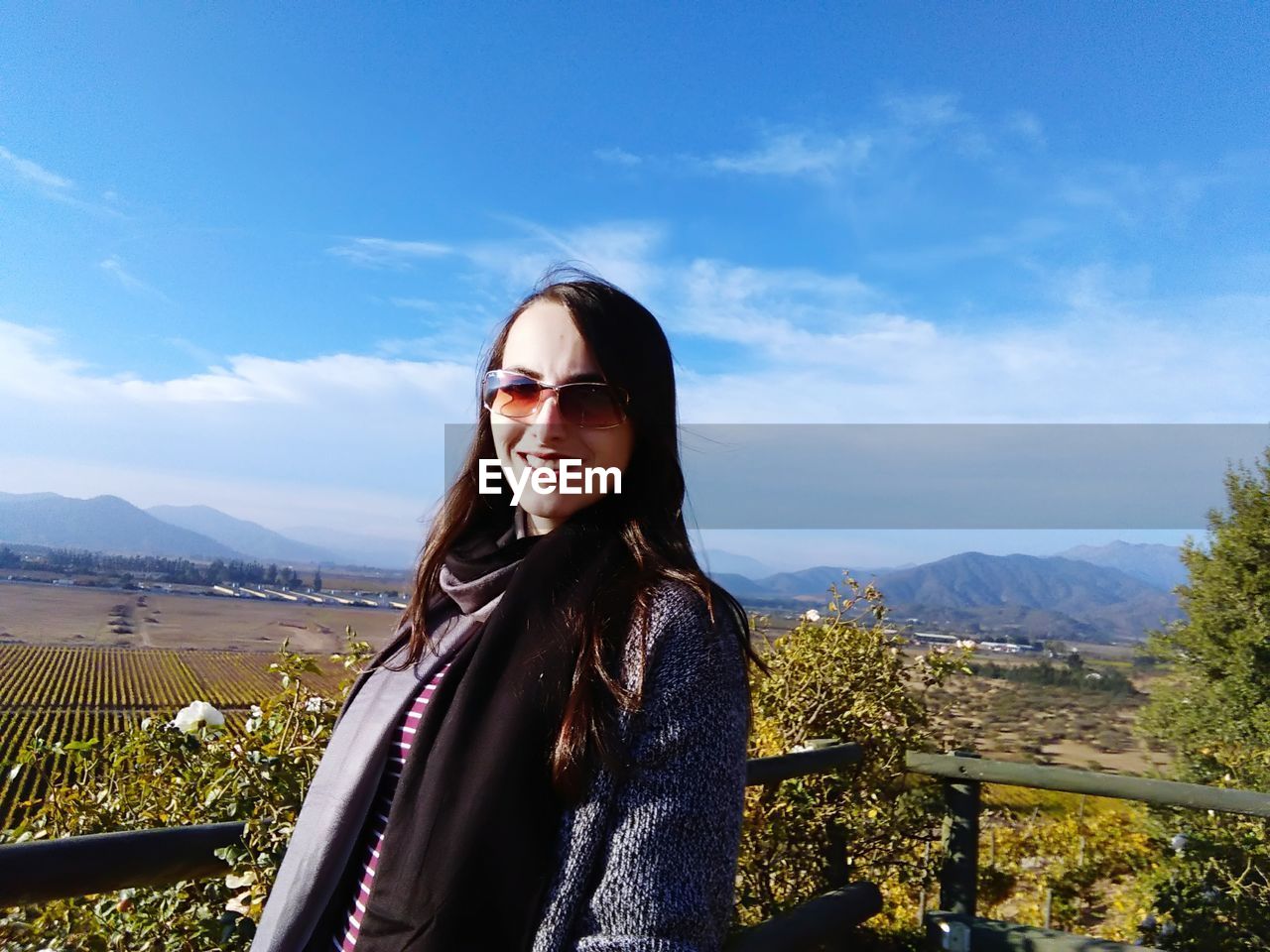 Portrait of young woman wearing sunglasses standing against mountain