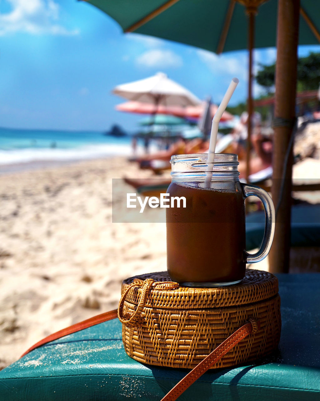 Close-up of drink on deck chair at beach against sky