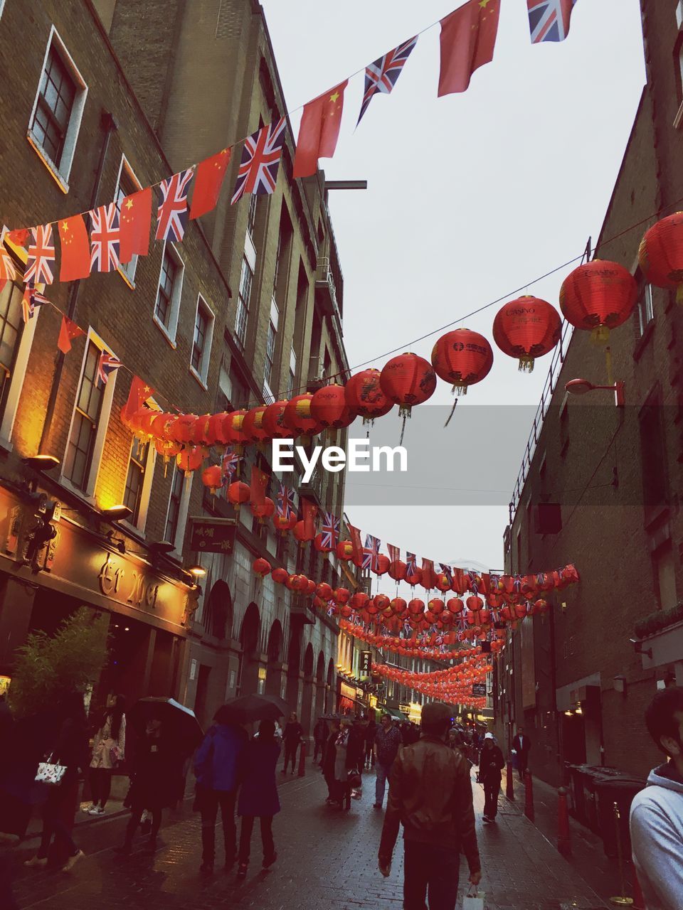 People walking on street with lanterns hanging amidst buildings in city