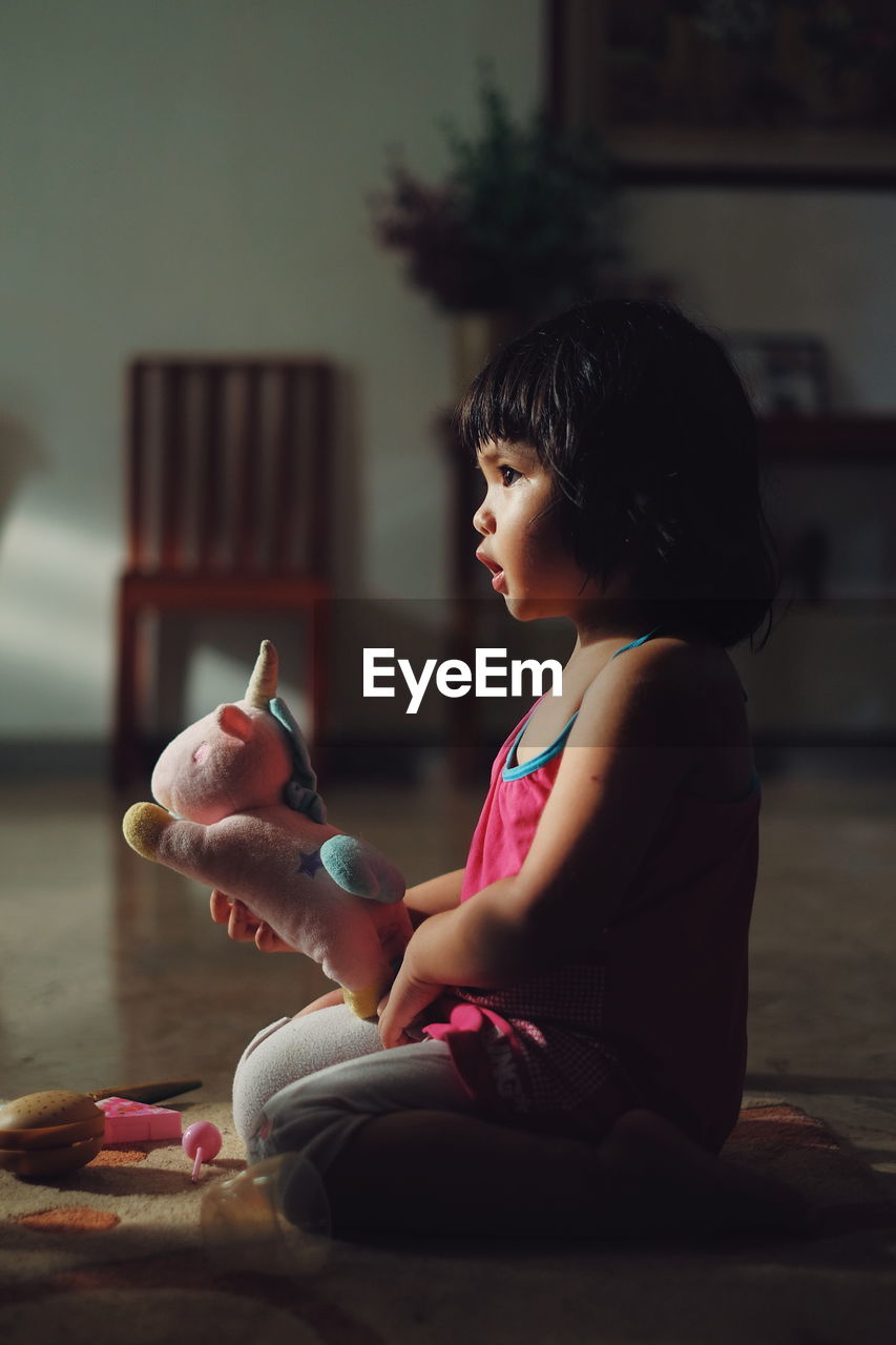 Side view of girl looking at toy at home