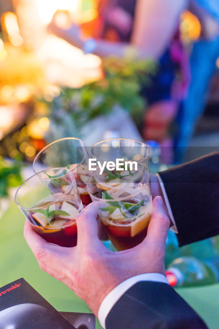 Cropped image of hands holding drinks in glasses