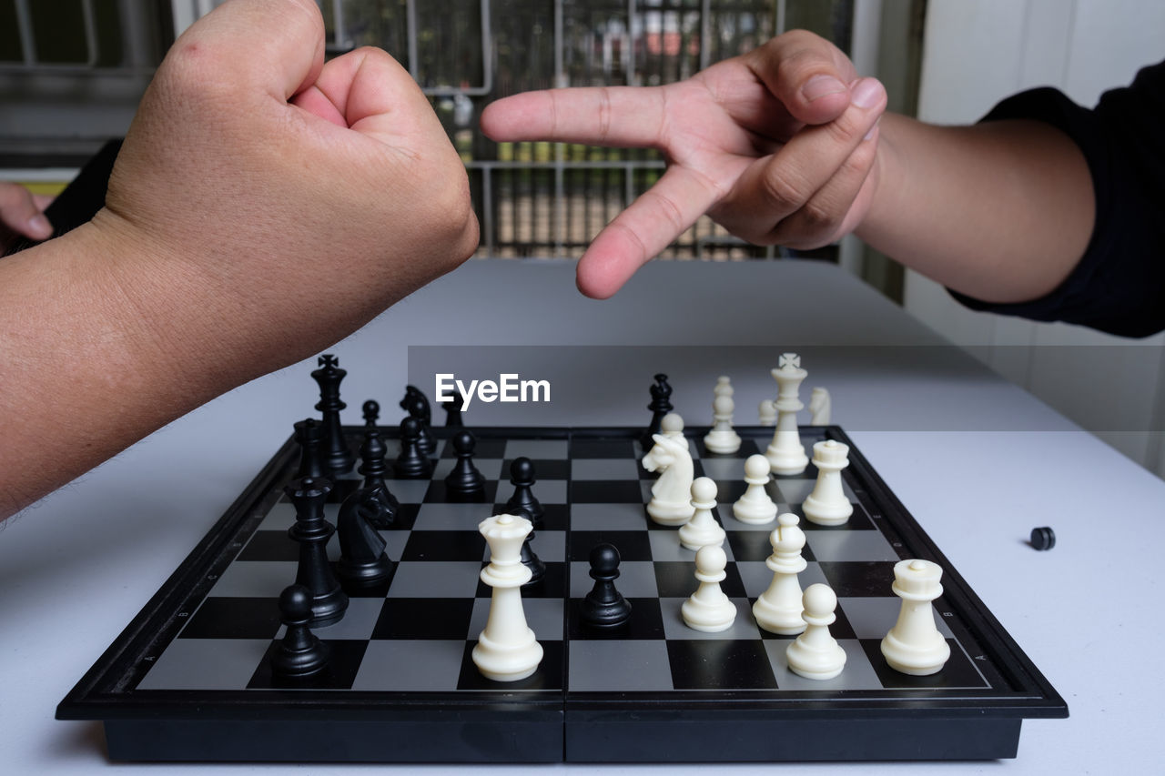 MIDSECTION OF PERSON PLAYING WITH CHESS PIECES IN A ROW