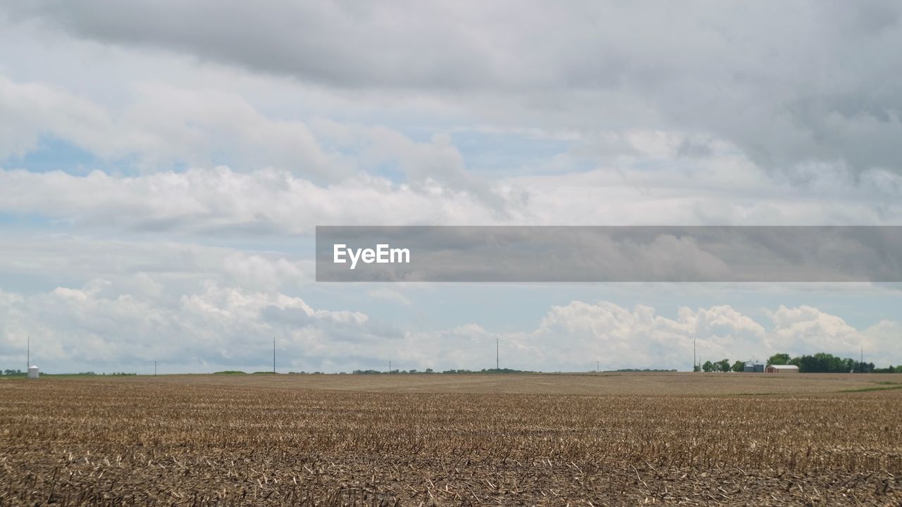 Scenic view of farm against cloudy sky