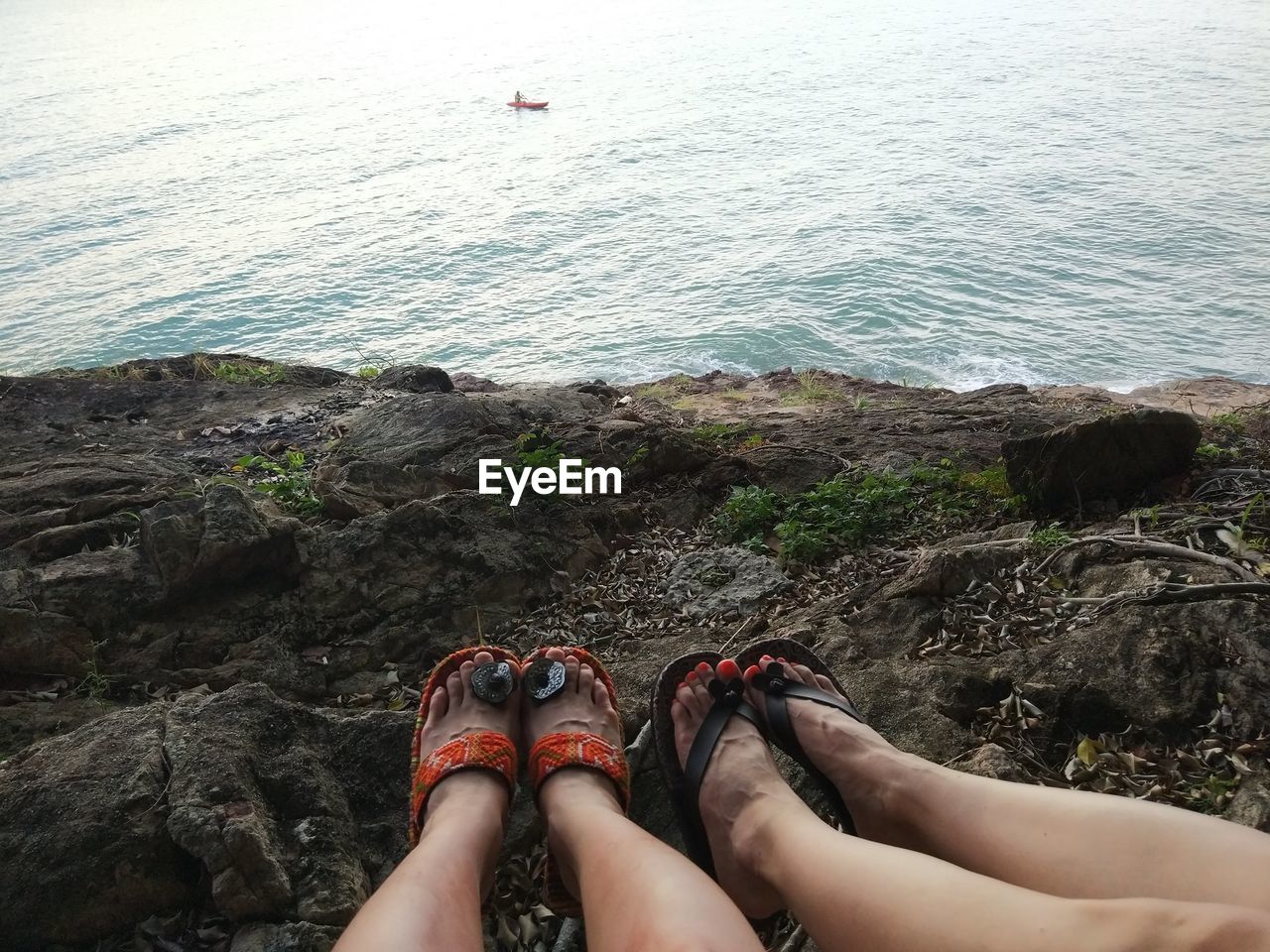 LOW SECTION OF WOMAN RELAXING ON ROCK AT SEA SHORE