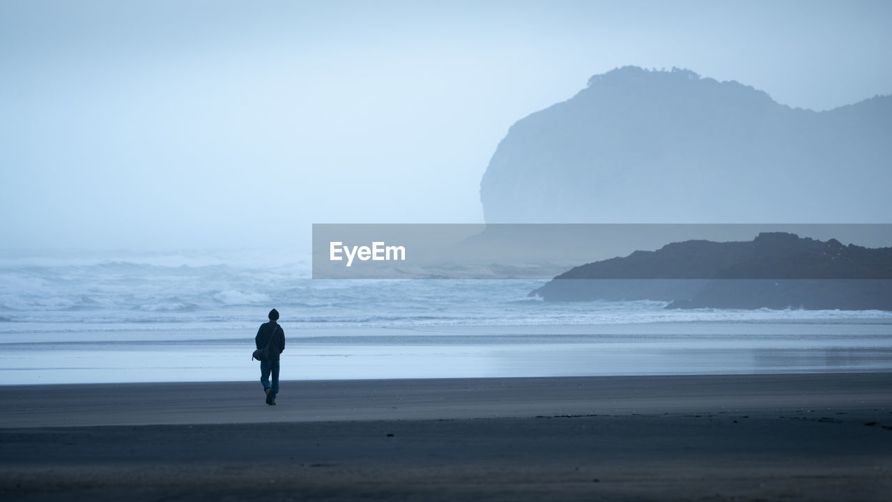 Rear view of silhouette man walking at beach