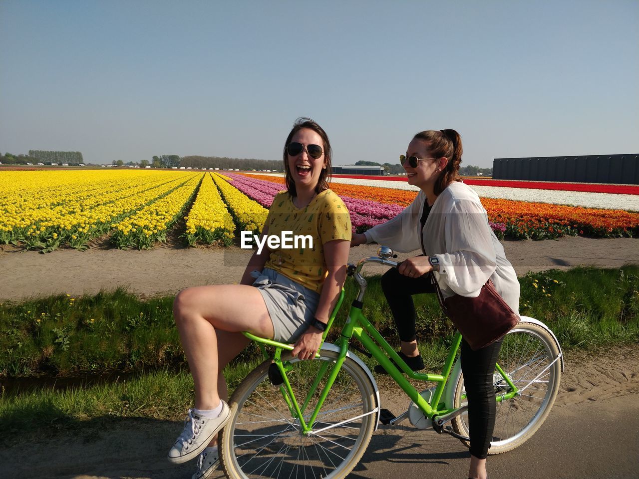 Full length of women standing with bicycle on street against clear sky
