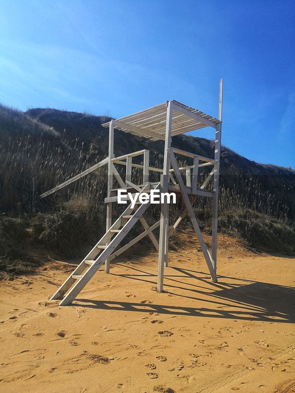 Lifeguard hut on field against blue sky