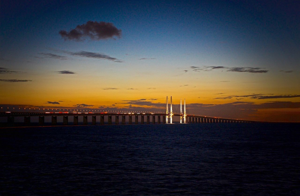 Scenic view of sea and bridge against sky during sunset