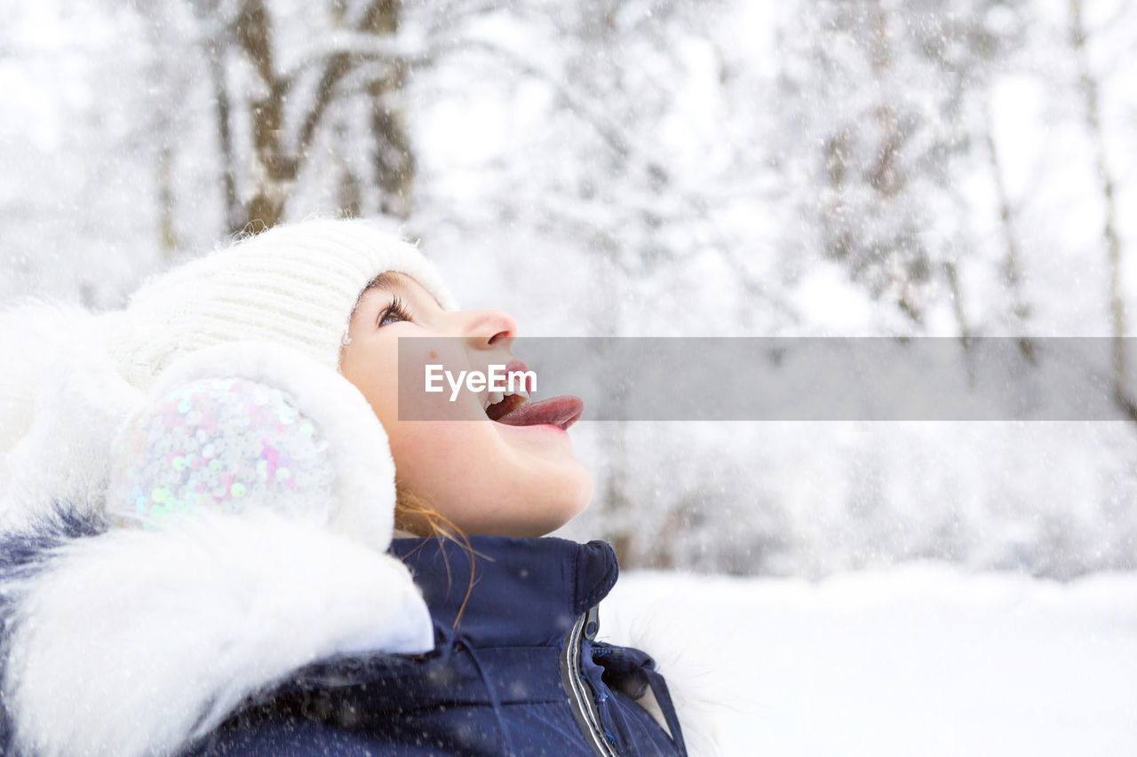 Close-up of girl with mouth open in forest during winter