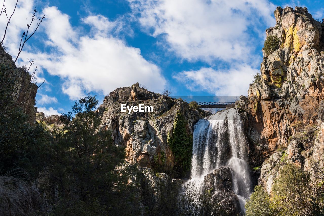 LOW ANGLE VIEW OF WATERFALL AMIDST ROCKS