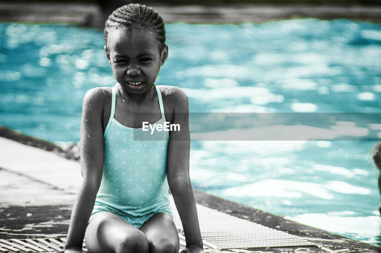 Close-up of wet girl sitting at poolside