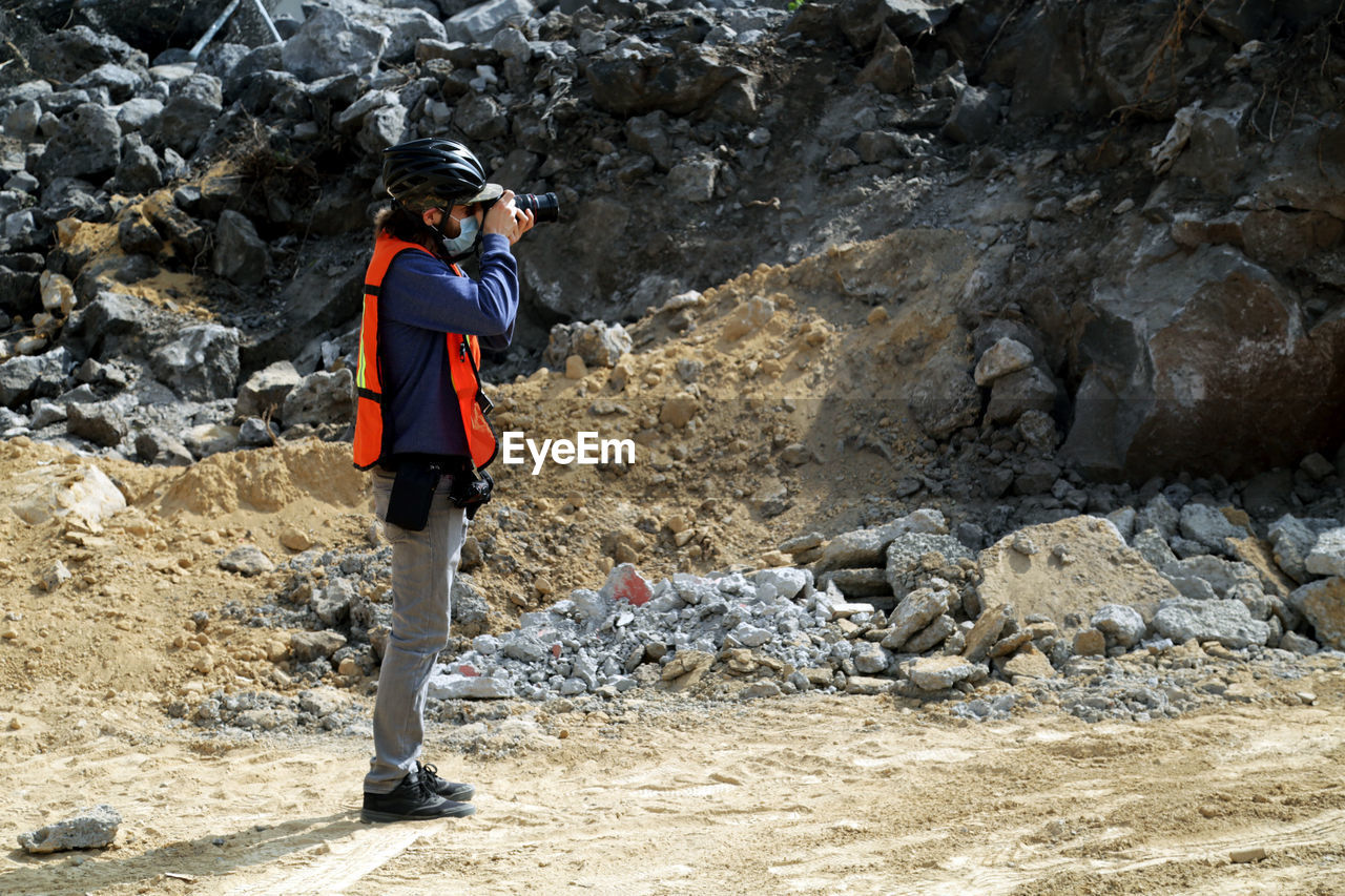 Medium close picture of a photographer taking pictures with rocks on the back