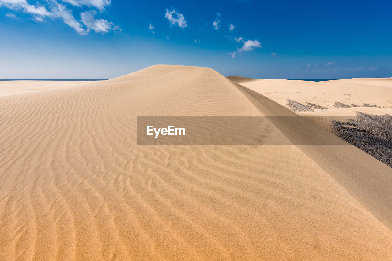 Scenic view of sand dunes against sky