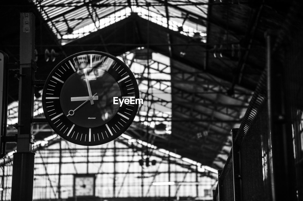 clock, time, architecture, built structure, indoors, no people, focus on foreground, number, accuracy, low angle view, circle, day, clock face, geometric shape, instrument of time, hanging, shape, railroad station, building, roof, minute hand, ceiling, wall clock