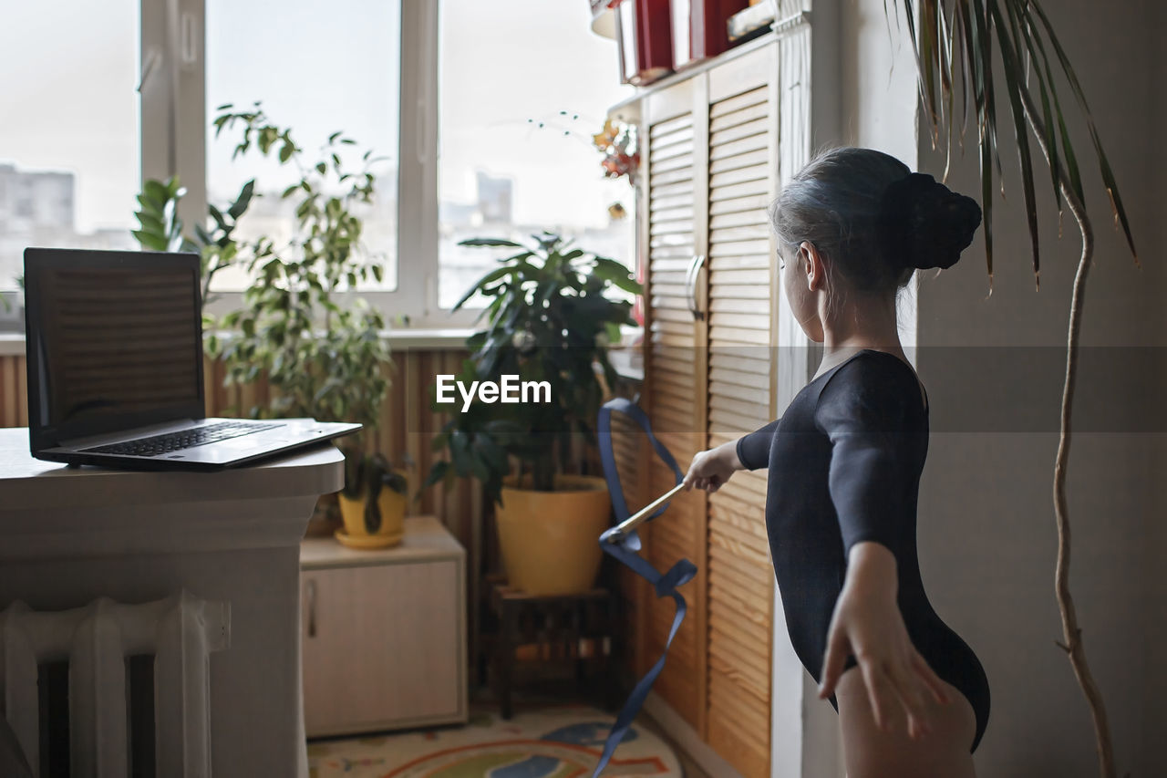 Side view of woman standing by window at home